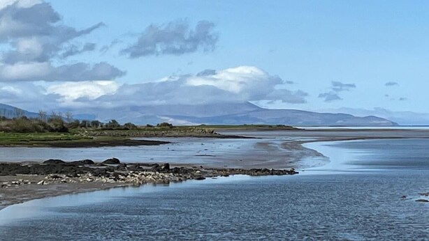 A riverbank with a calm water body, rocky shoreline, and distant mountains under a partly cloudy sky. - Tiny House Glamping - On the Wild Atlantic Way 5 minutes from Tralee (Tralee)