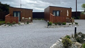 Two wooden cabins with outdoor seating, a gravel driveway, and a cloudy sky. - Tiny House Glamping - On the Wild Atlantic Way 5 minutes from Tralee (Tralee)