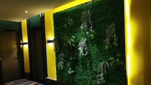 A hallway with a green vertical garden wall, a yellow accent wall, and a patterned carpet. - Ganmu Gardens Hotel (Susong)