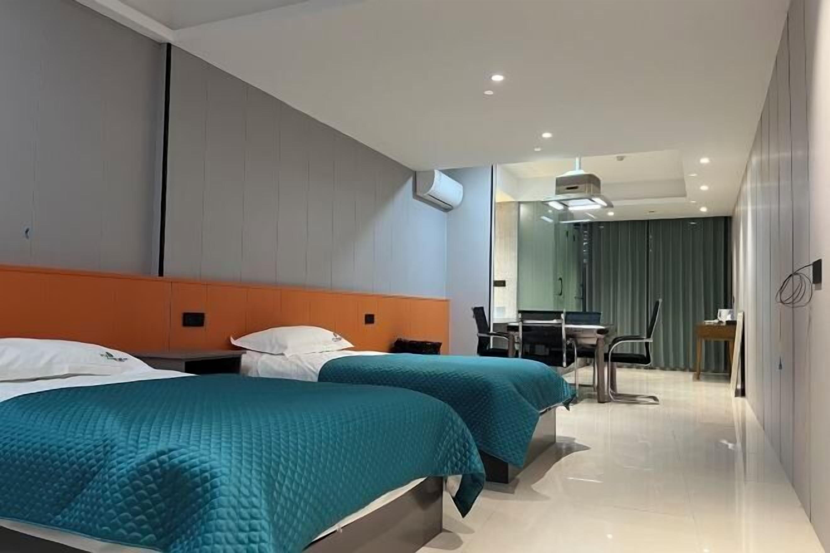 A hotel room with two beds, a desk, and a chair.