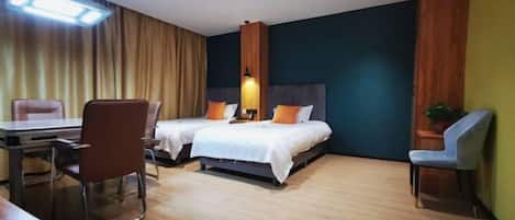 A hotel room with two beds, a desk, and a chair.