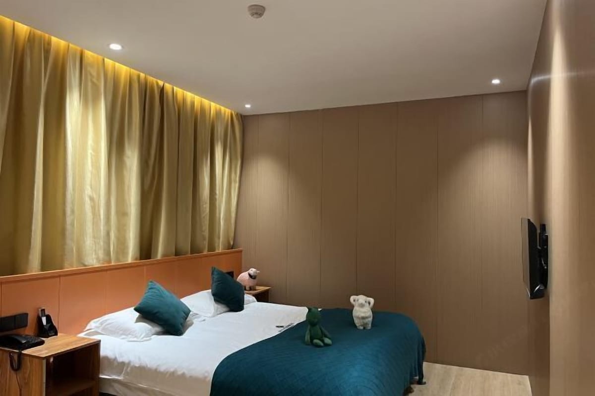A hotel room with a bed, a nightstand, a telephone, and a wall-mounted TV.