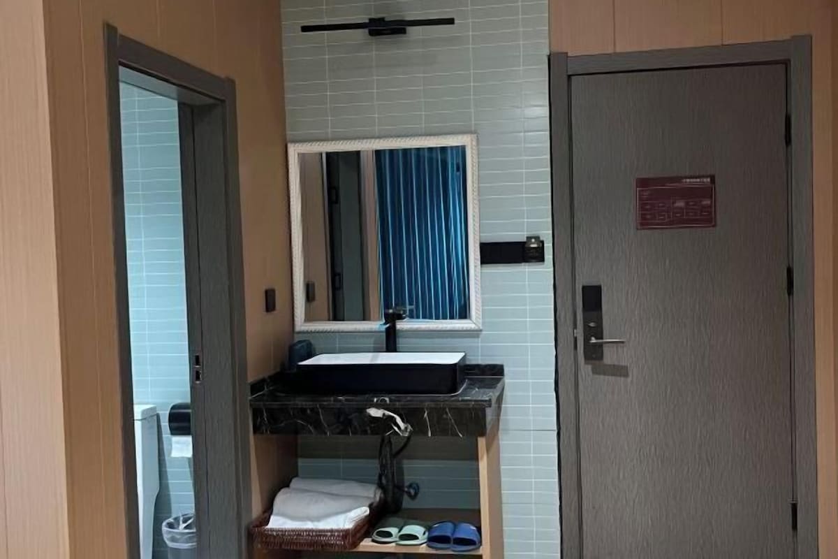 A bathroom with a sink, mirror, and towel rack. There is a door with a sign on it.