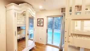 Une chambre avec un lit superposé, un grand miroir et une porte-fenêtre coulissante donnant sur un balcon.