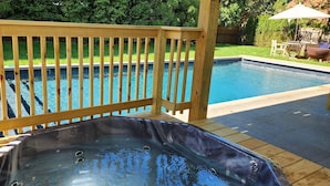 Une terrasse en bois avec un jacuzzi et une piscine.