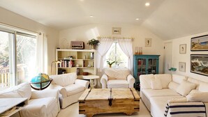 Un salon avec des meubles blancs, un globe posé sur une table d’appoint et une bibliothèque.