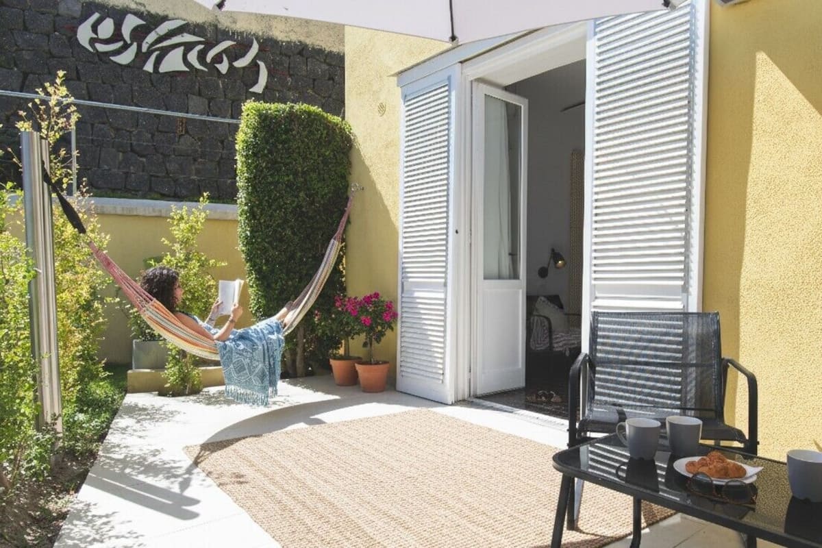 Eine Terrasse mit einer Hängematte, einem Tisch mit Stühlen und Topfpflanzen.