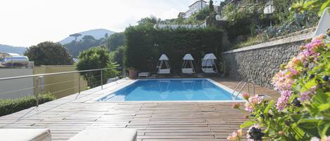 Una piscina al aire libre de temporada, tumbonas