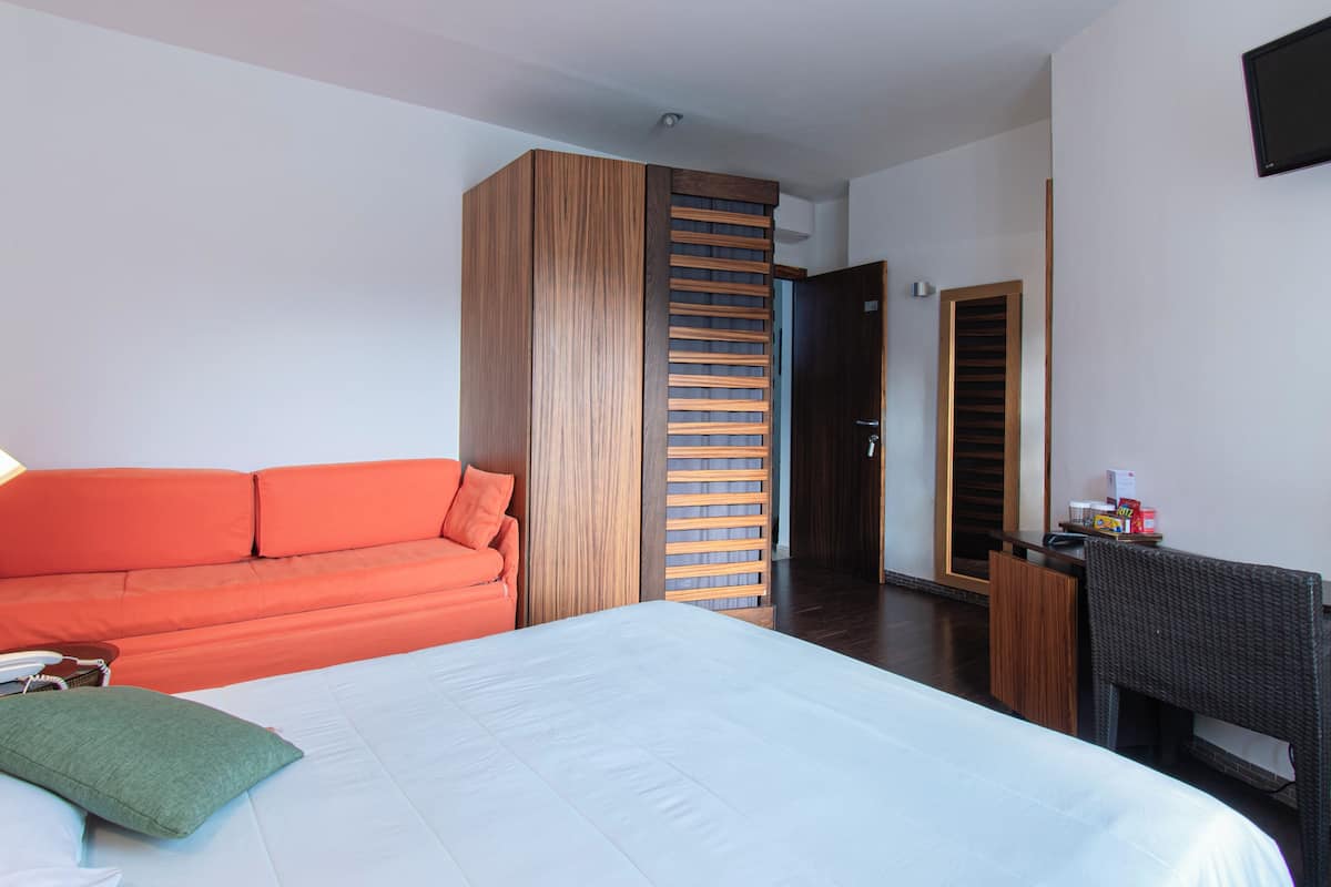 Ein Hotelzimmer mit Bett, Sofa, Schreibtisch und Kleiderschrank.