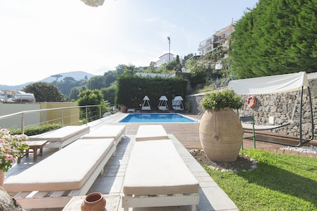 Una piscina al aire libre de temporada, sillones reclinables de piscina