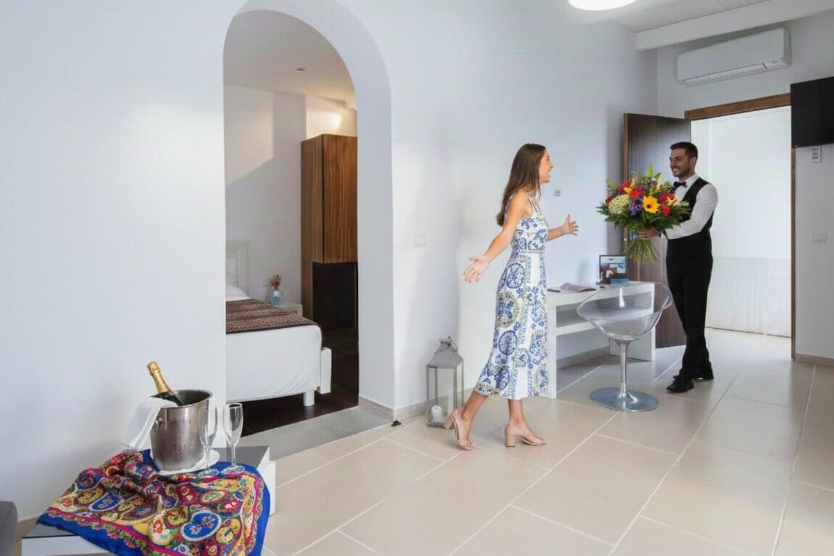 Eine Hotellobby mit einer Rezeption, einer Sitzecke und einer Treppe.