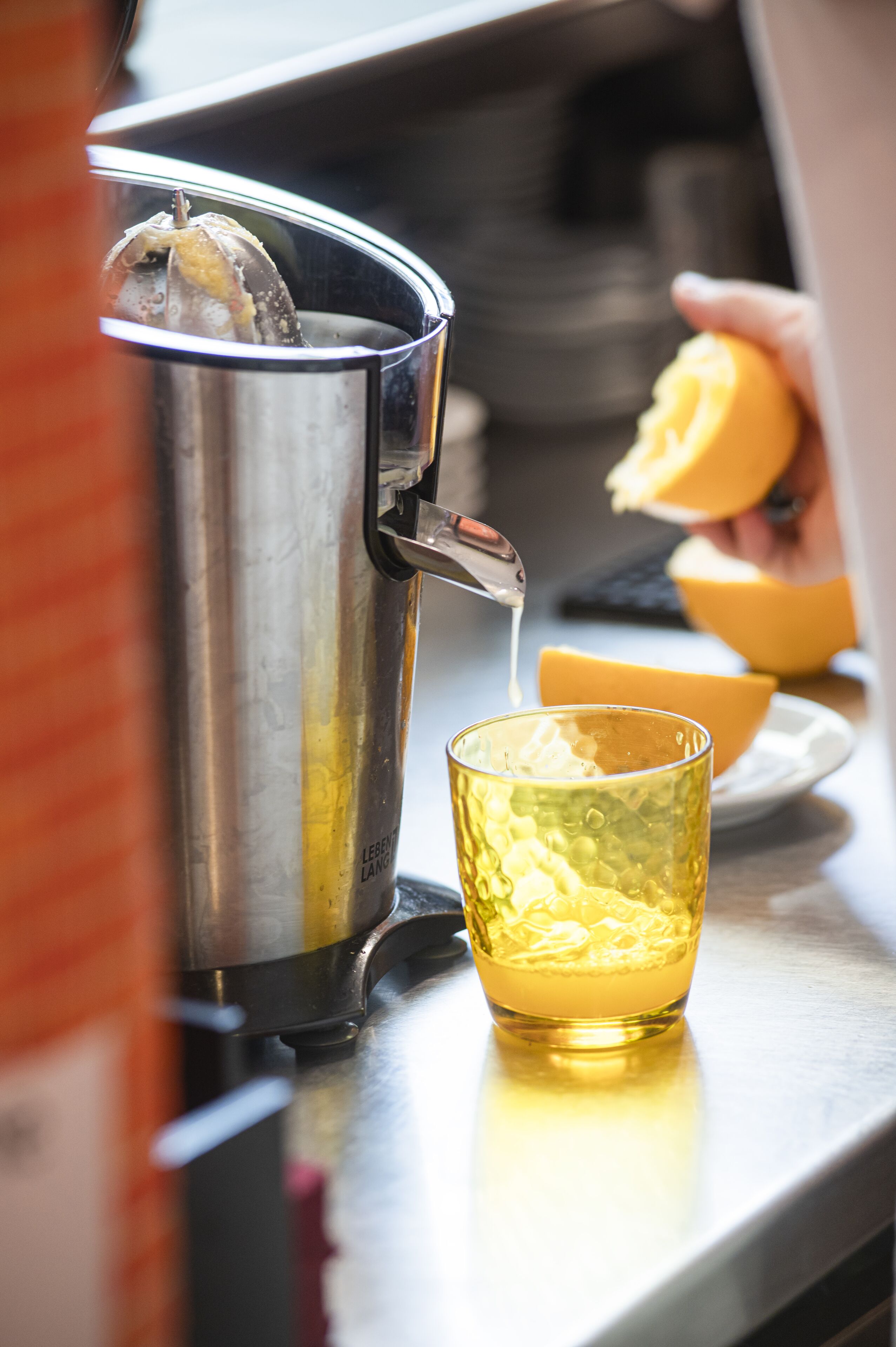Un extracteur de jus avec un verre de jus posé sur un plan de travail.