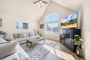 A living room with a sofa, coffee table, TV, and decorative vase. - Cozy Home 1 Mile to Downtown CDA & Lake – King Beds and an EV Charger! (Coeur d'Alene)