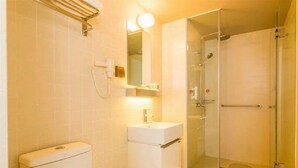 A bathroom with a toilet, sink, mirror, and glass-enclosed shower. - Jinjiang Inn Select (Qingdao)