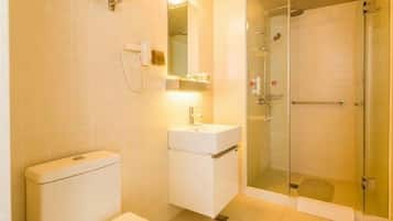 A bathroom with a toilet, sink, mirror, and glass-enclosed shower.