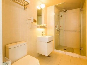 Un bany amb vàter, rentatge, mirall i plat de dutxa amb envàs de vidre.