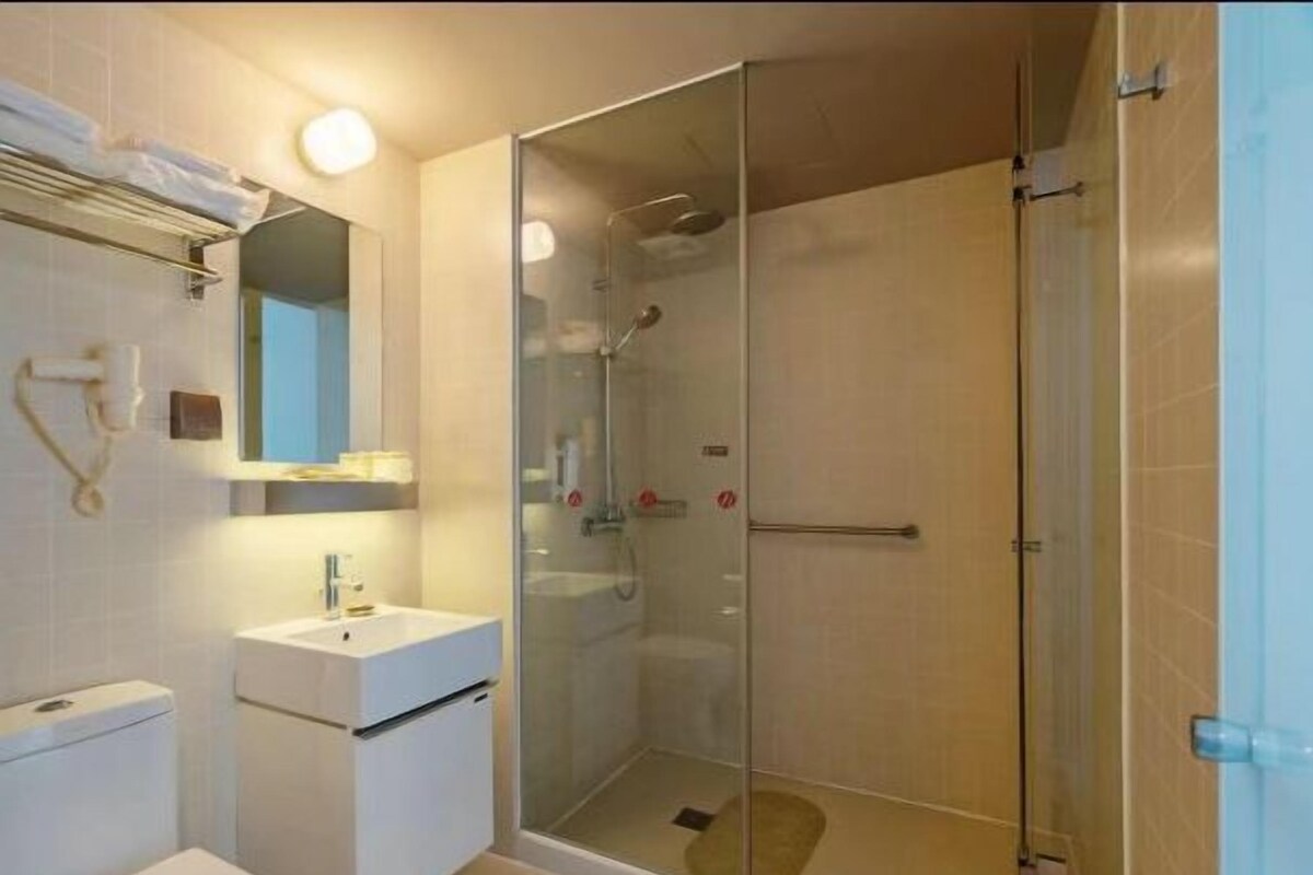 A modern bathroom with a glass-enclosed shower, a white sink, and a toilet.