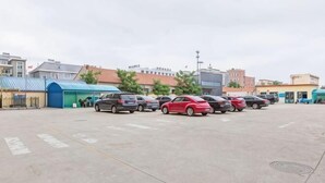 A parking lot with several cars, buildings in the background, and a blue structure on the left. - Jinjiang Inn Select (Qingdao Boli Dongjiakou) (Qingdao)
