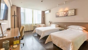 A hotel room with two beds, a desk with a computer, a chair, a TV, and a window with curtains. - Jinjiang Inn Select (Qingdao)