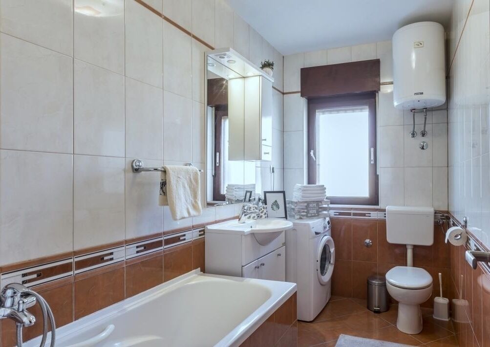 Un bagno moderno con vasca, lavabo, lavatrice e WC.