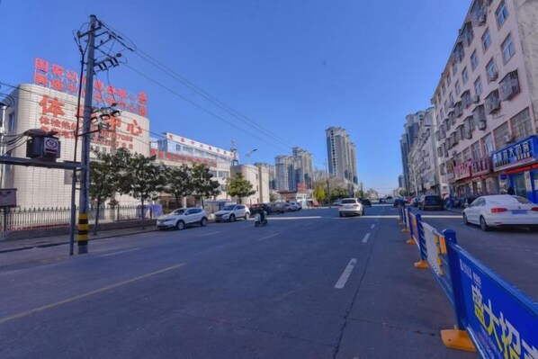 Une vue de rue avec des bâtiments, des voitures et un ciel dégagé.