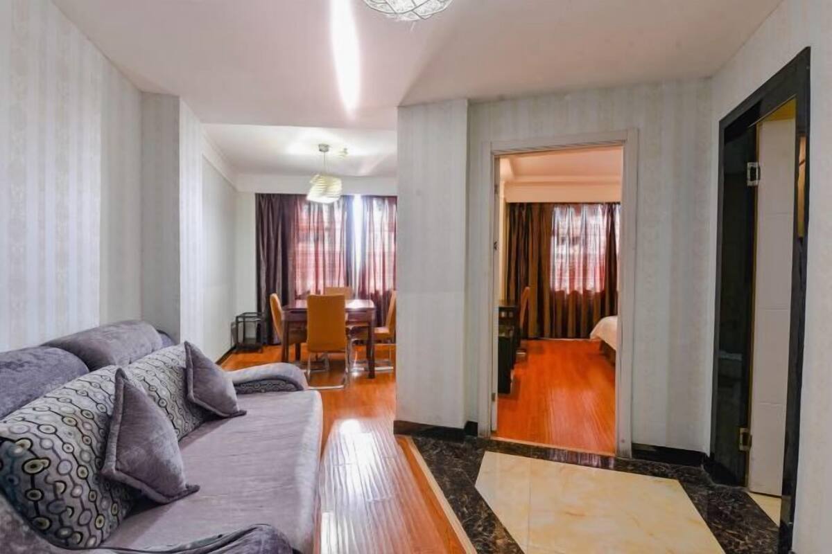 Habitació d'hotel amb un sofà, una taula de menjador i un passadís que condueix a una altra habitació.