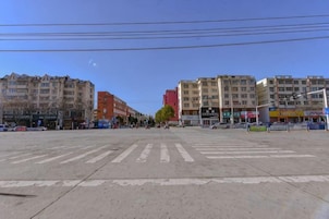 Un paso de peatones amplio, con edificios a ambos lados, incluyendo uno rojo y otro amarillo.