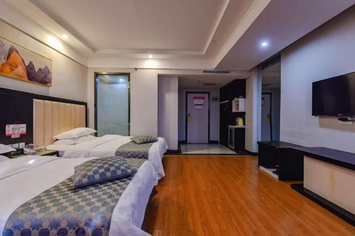 Habitació d'hotel amb dos llits, una televisió, una taula de nit i un mirall.
