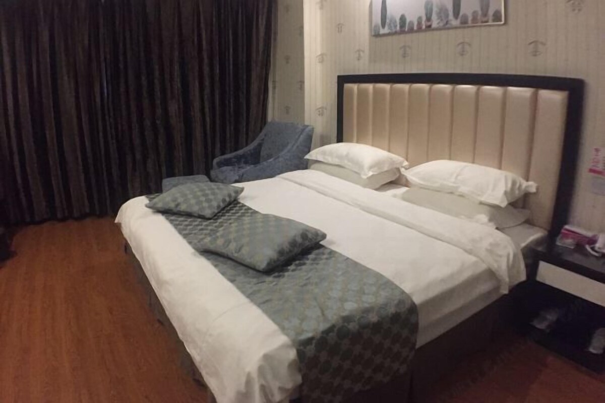 Una habitación de hotel con una cama, una silla, una mesita de noche y una cortina.
