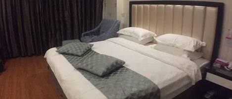 A hotel room with a bed, a chair, a nightstand, and a curtain.