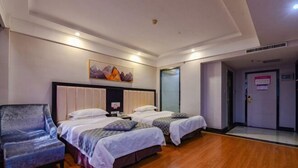 A hotel room with two beds, a chair, a painting on the wall, and a door to another room.