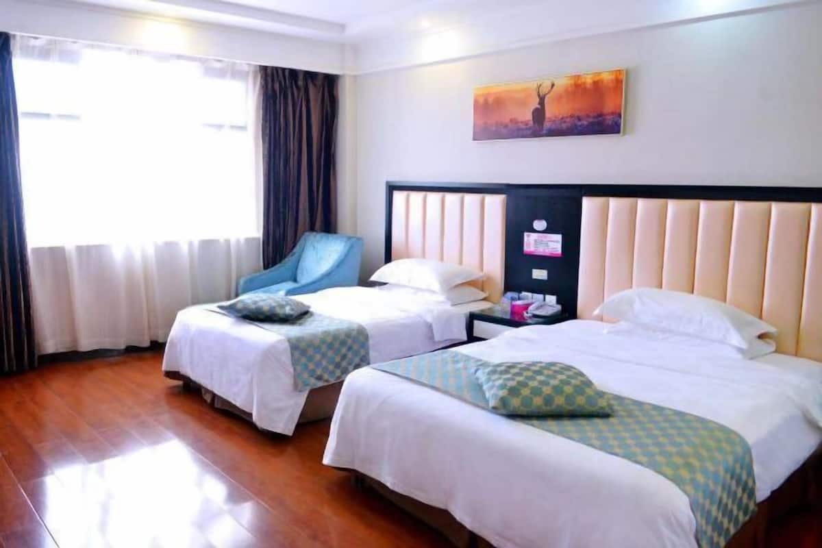 Habitació d'hotel amb dos llits, una cadira, un quadre i una tauleta de nit.