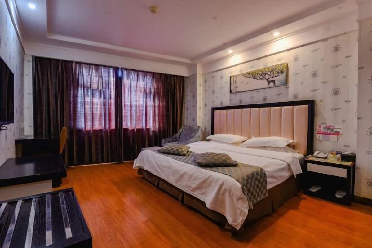 Habitació d'hotel amb llit, escriptori, cadira i finestra amb cortines.