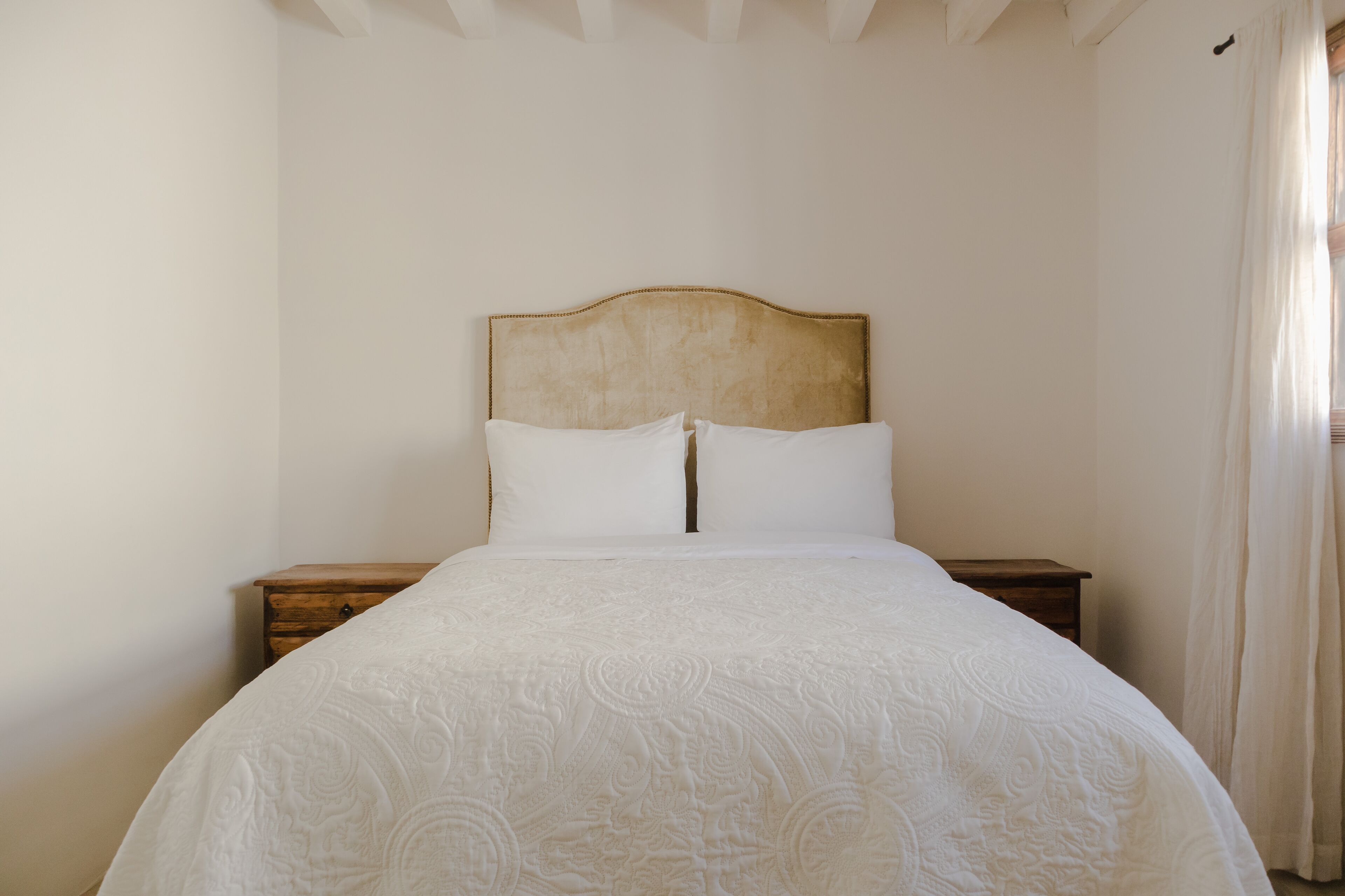 Una cama bien hecha con un edredón estampado, un cabecero de madera y dos mesitas de noche.