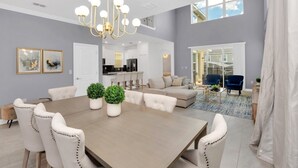 A spacious living room with a large dining table, comfortable seating, a chandelier, and a view of the kitchen and dining area. - Fantastic 5 Bedroom Champions Gate Resort Home With Spa and Pool (Davenport)