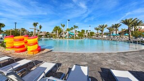 A pool area with lounge chairs, palm trees, and a water slide. - Fantastic 5 Bedroom Champions Gate Resort Home With Spa and Pool (Davenport)