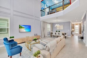Un salon spacieux avec une grande télévision, un canapé, une table basse et un coin repas.