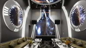 A modern hotel lobby with a central seating area, two large circular wall decorations, and a large screen displaying a cosmic scene. - Master Hotel (Huidong)