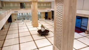 A spacious lobby with a high ceiling, large columns, and a checkered floor pattern. - Master Hotel (Huidong)