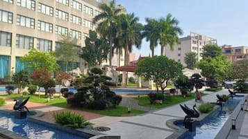 Un patio de hotel con fuente de agua, palmeras y un edificio moderno.