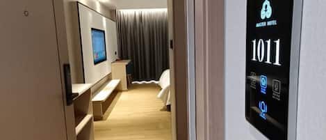 A modern hotel room with a digital display showing room number 1011, a television, a bed, and a bathroom with a shower.