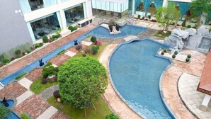 A rooftop swimming pool with a surrounding garden and a modern building in the background. - Master Hotel (Huidong)