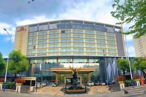 A large hotel with a curved facade, multiple floors, and a central entrance with a decorative fountain. - Master Hotel (Huidong)