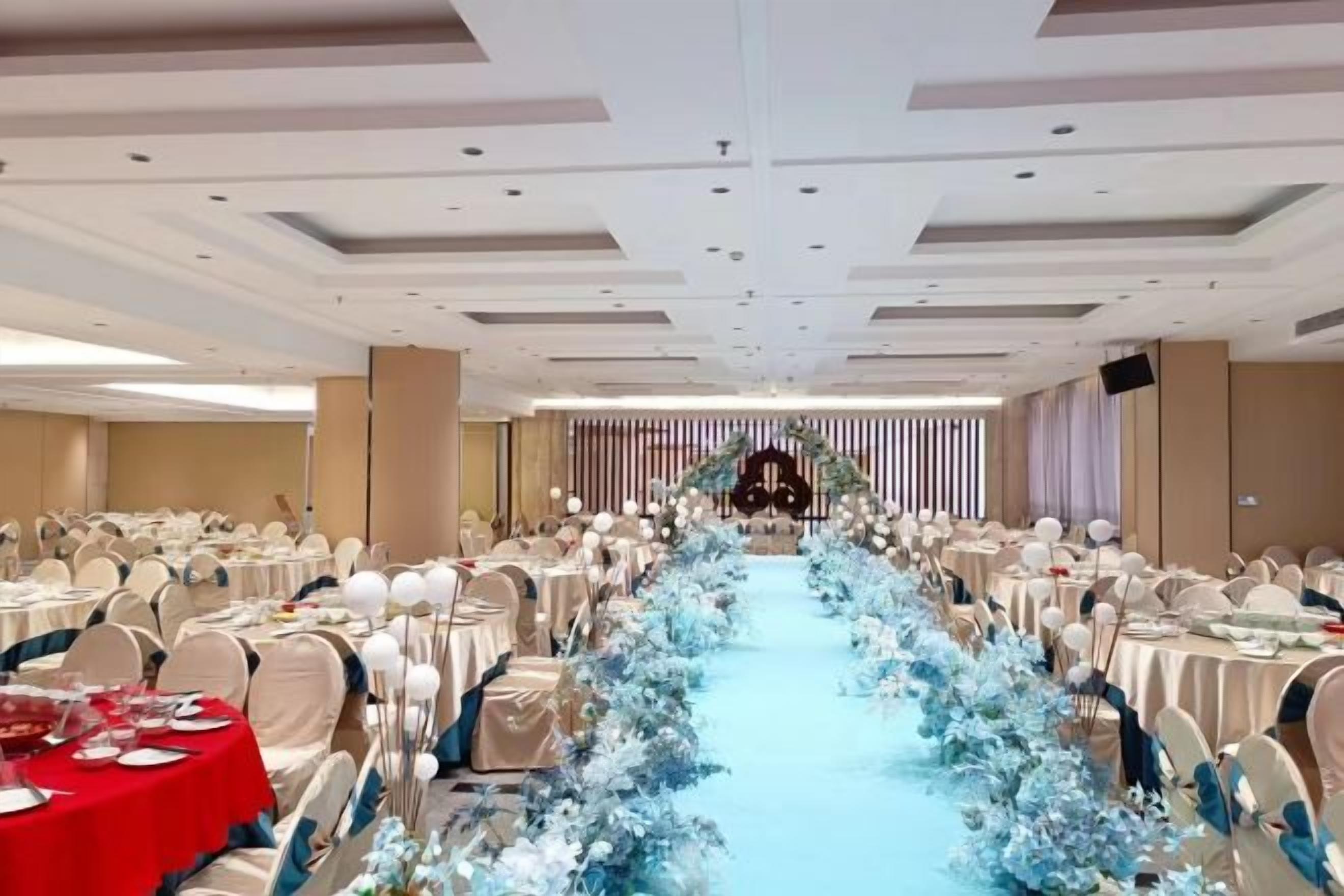 A banquet hall with rows of tables, a central aisle, and a stage at the front.