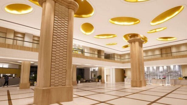 A spacious lobby with large columns, a high ceiling with circular lights, and a check-in counter. - Master Hotel (Huidong)