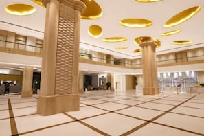 A spacious lobby with large columns, a high ceiling with circular lights, and a check-in counter. - Master Hotel (Huidong)