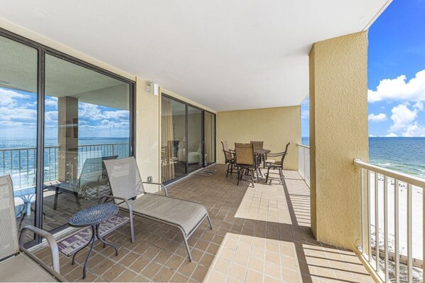 A balcony with a view of the ocean, furnished with chairs and a table. - Summer House 1105A (Orange Beach)