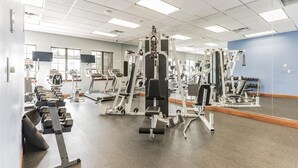 A gym with various exercise equipment, including treadmills, weight machines, and free weights.