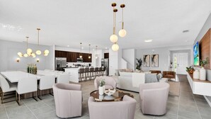 Un salon moderne comprenant un coin repas, une cuisine et un escalier menant à un autre niveau.