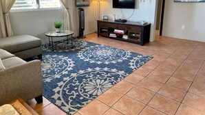 A living room with a sofa, a TV mounted on the wall, a floor lamp, and a patterned rug. - Family time, 5 minute walk from main walkway to restaurants and beach! (Vieques)